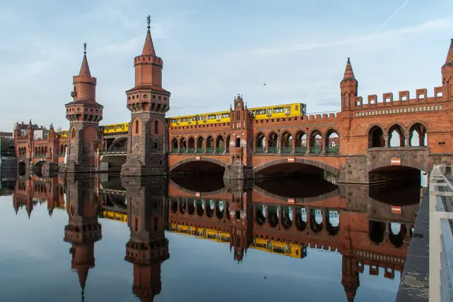 The red-brick Oberbaumbrücke reflected in the Spree, with a yellow train crossing