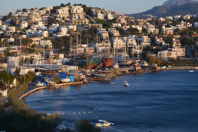 Yamaçtaki beyaz evlerin önünde tekneler ve Bodrum limanı