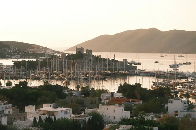 Akşam ışığında marina ve Bodrum Kalesi, arkada tepeler