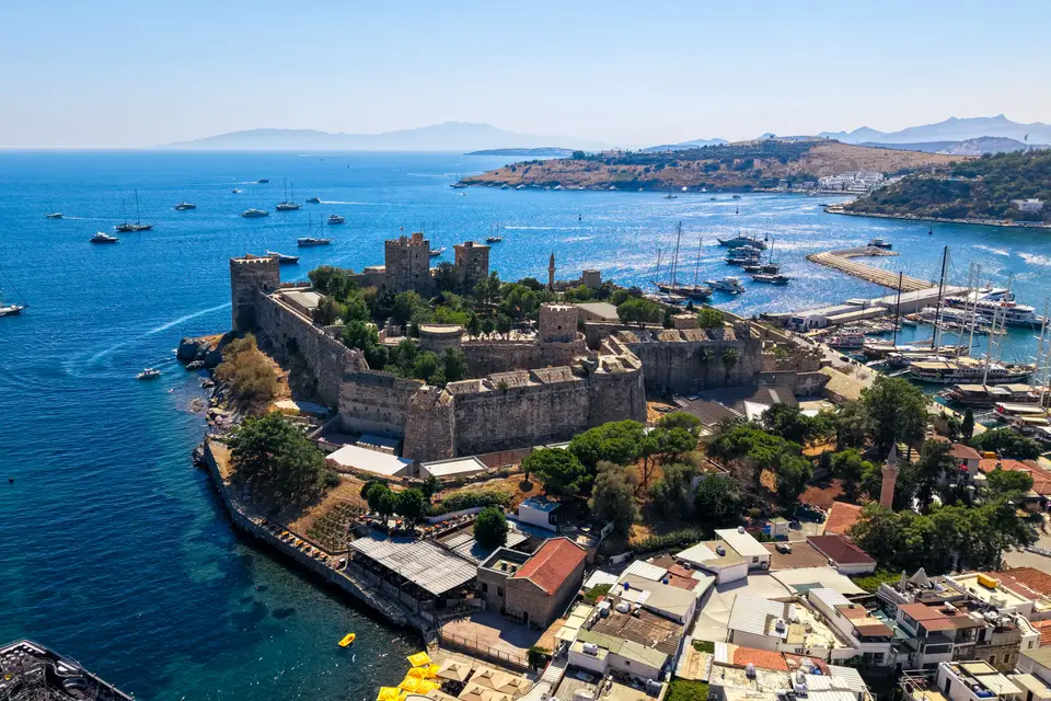Mavi denizle çevrili Bodrum Kalesi'nin havadan görünüşü, arkada tekneler ve kıyı
