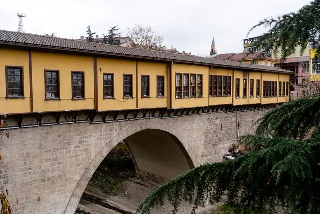 Üzerinde sarı cepheli dükkânlar sıralanan taş kemerli Irgandı Köprüsü