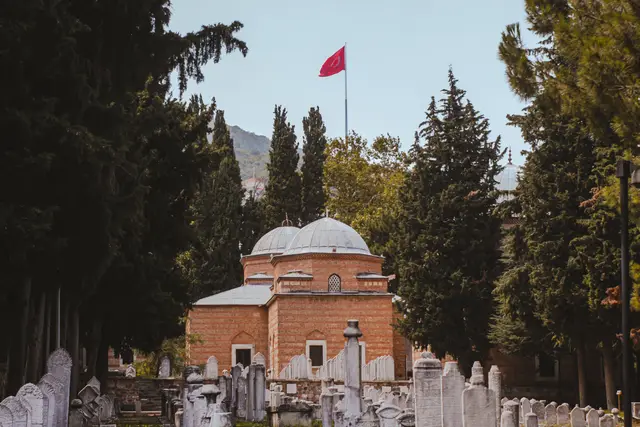 Muradiye Külliyesi'nin servili bahçesinde mezar taşları ve kubbeli bir türbe