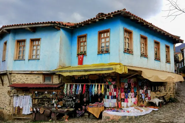 Cumalıkızık'ta mavi boyalı iki katlı eski bir evin önündeki köy tezgâhı