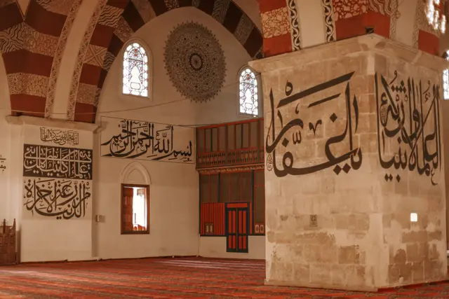 Inside the Old Mosque: stone piers with large calligraphy and red-and-white arches