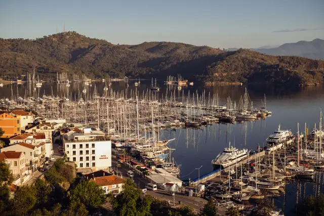 Fethiye marina with moored sailing boats and the mountains behind at sunset