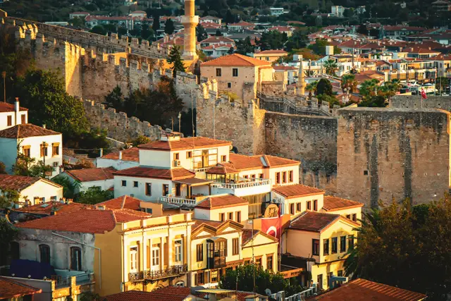 Gün batımında Çeşme Kalesi'nin surları ve kiremit çatılı evler