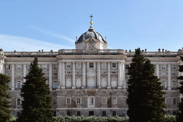 The domed façade of the Royal Palace of Madrid framed by trees