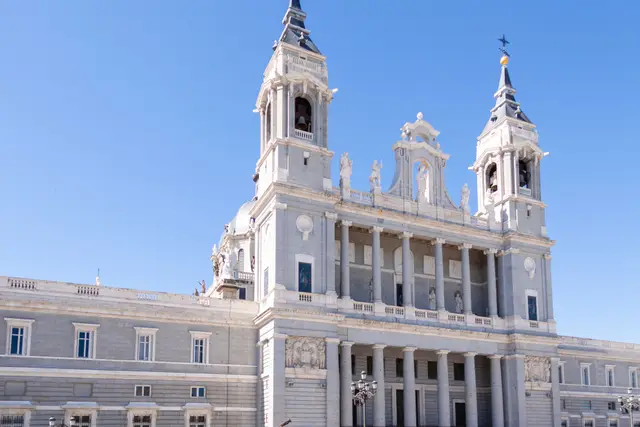 The twin-towered façade of Almudena Cathedral under a blue sky