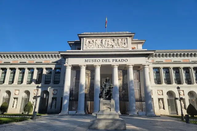 The colonnaded main façade of the Prado Museum with the statue in front