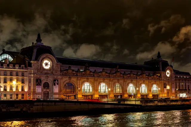 Gece ışıklandırılmış Musée d'Orsay ve Seine'deki yansıması