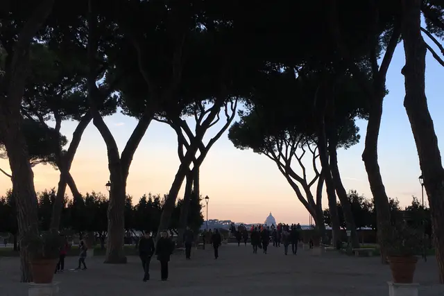 Aventino'daki Giardino degli Aranci'de gün batımı; ağaçların arasından uzakta San Pietro kubbesi